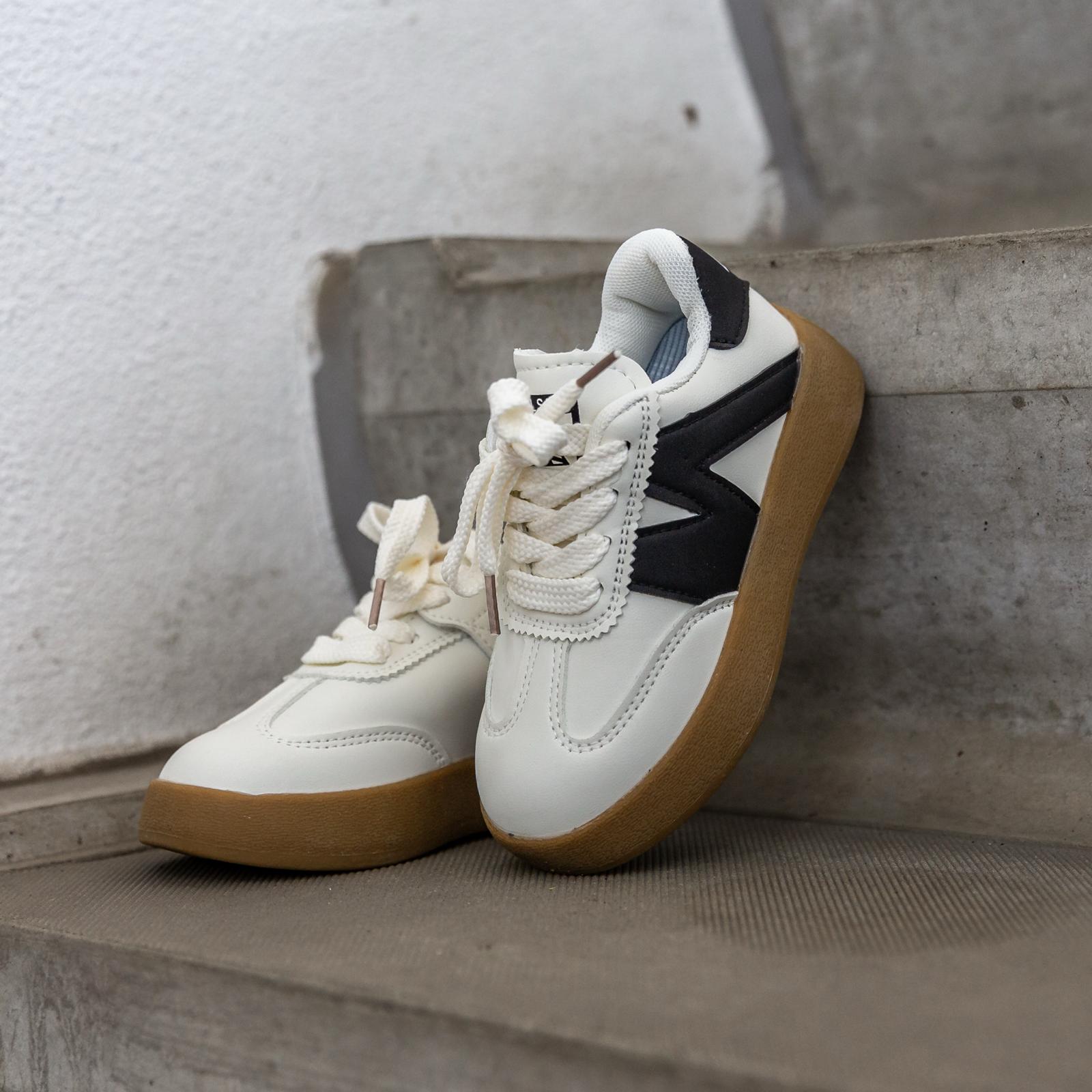 Schuin bovenaanzicht van de Sunnyz Black – moderne witte kindersneaker met zwart detail voor een sportieve look