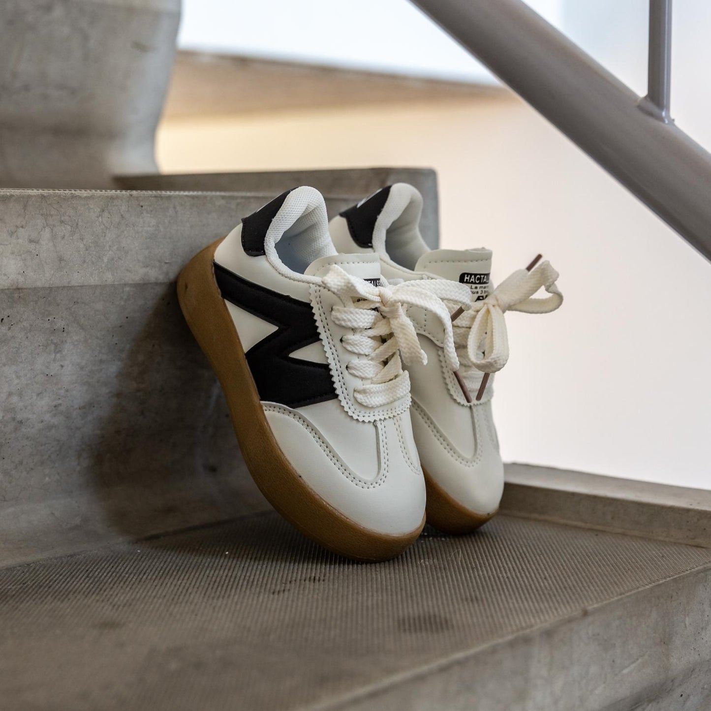Vooraanzicht van de Sunnyz Black – witte kindersneaker met opvallend zwart logo, perfect voor jongens en meisjes
